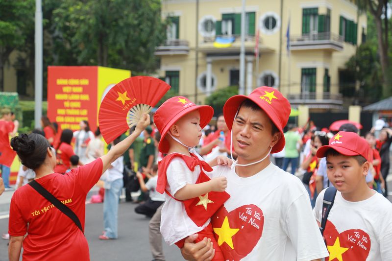Một em bé trong vòng tay người thân đang di chuyển về hướng Quảng trường Ba Đình.