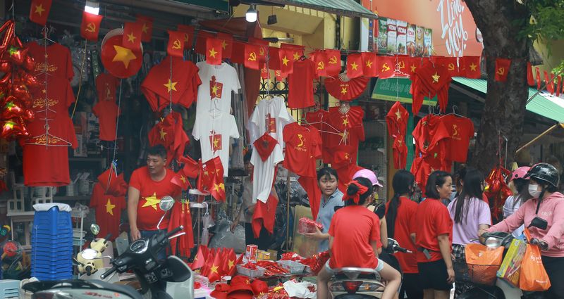 Một điểm bán quần áo in hình lá cờ Tổ quốc và các sản phẩm lưu niệm tấp nập người mua.