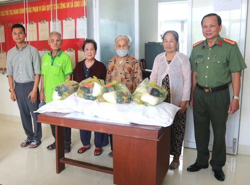 Ông Võ Văn Lập - Trưởng Công an xã Giao Long (bìa phải) và ông Mai Quốc Dũng - Tổng giám đốc đại diện Công ty Cổ phần Mẹ và Bé Dũng Jerry (bìa trái) trao quà cho đại diện các gia đình chính sách

