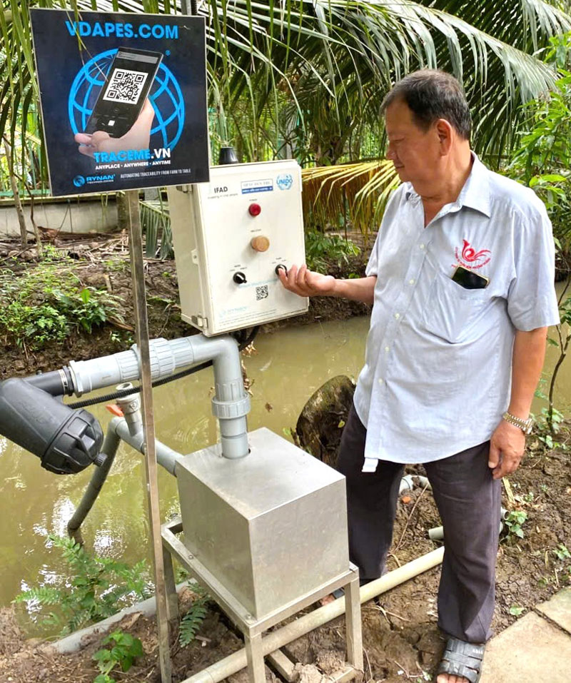 Nông dân Nguyễn Văn Bảy bên hệ thống tưới tự động.