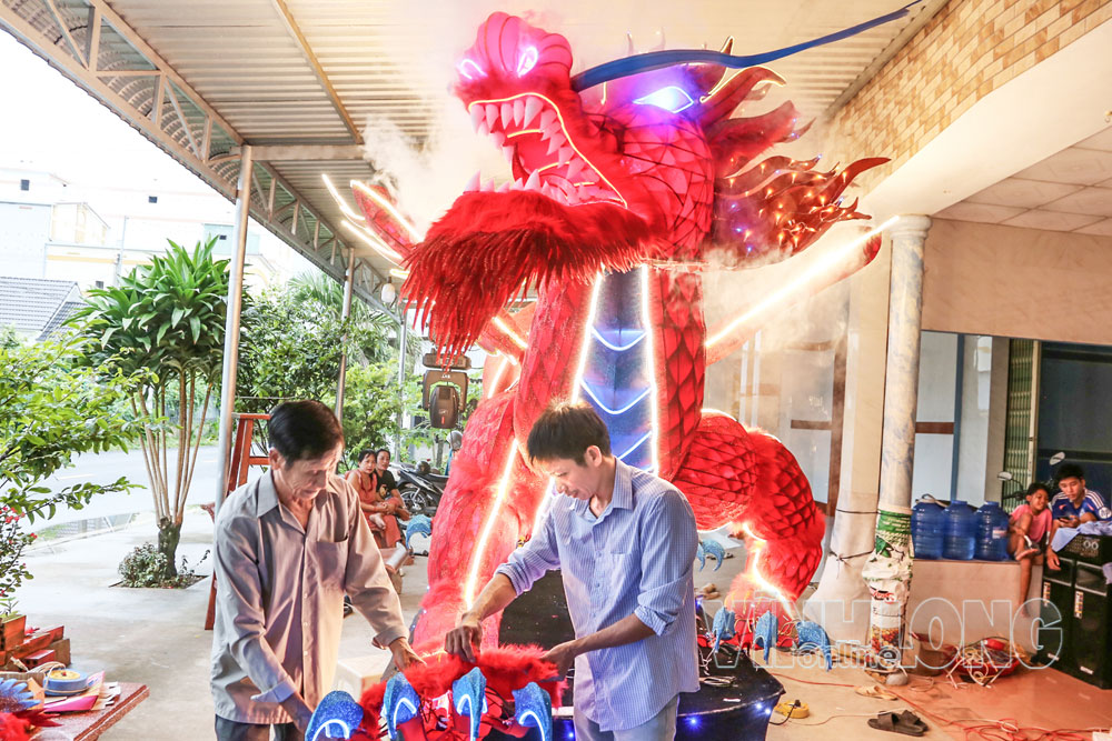 Ông Trầm Văn Hận và con trai đang hoàn thiện những chi tiết của lồng đèn “Kỳ lân phi vũ”. Ảnh: NGỌC XOÀN