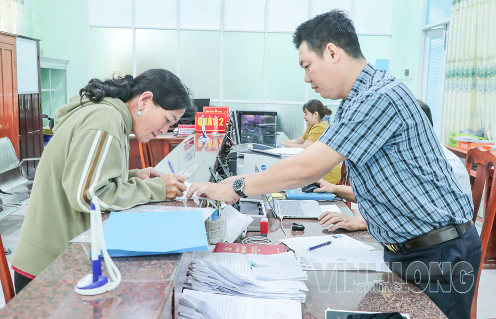Cán bộ Trung tâm Phục vụ hành chính công xã Long Vĩnh hướng dẫn bà Võ Thị Bàn, ấp Vàm Rạch Cỏ, làm hồ sơ xin việc.

