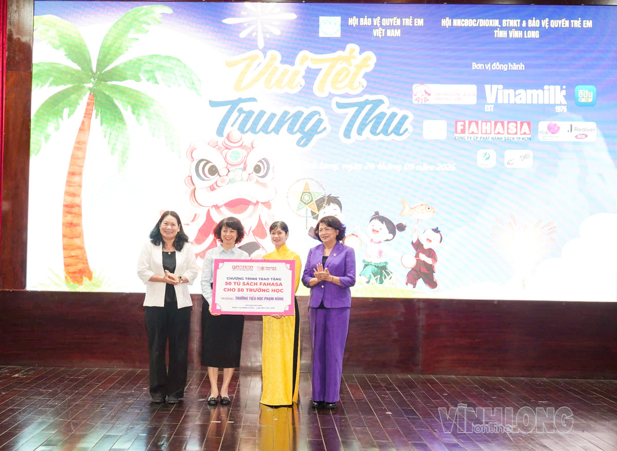 Đại diện Công ty CP Phát hành sách TP Hồ Chí Minh (FAHASA) trao biểu trưng tặng tủ sách cho Trường Tiểu học Phạm Hùng.