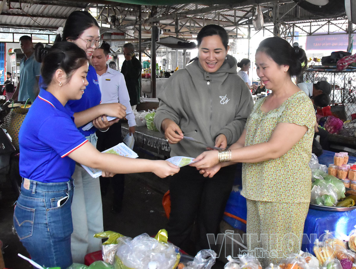 Cán bộ địa phương và lực lượng MobiFone Vĩnh Long phát tờ rơi hướng dẫn tiểu thương phòng tránh các hình thức lừa đảo trực tuyến tại chợ Vinh Kim.