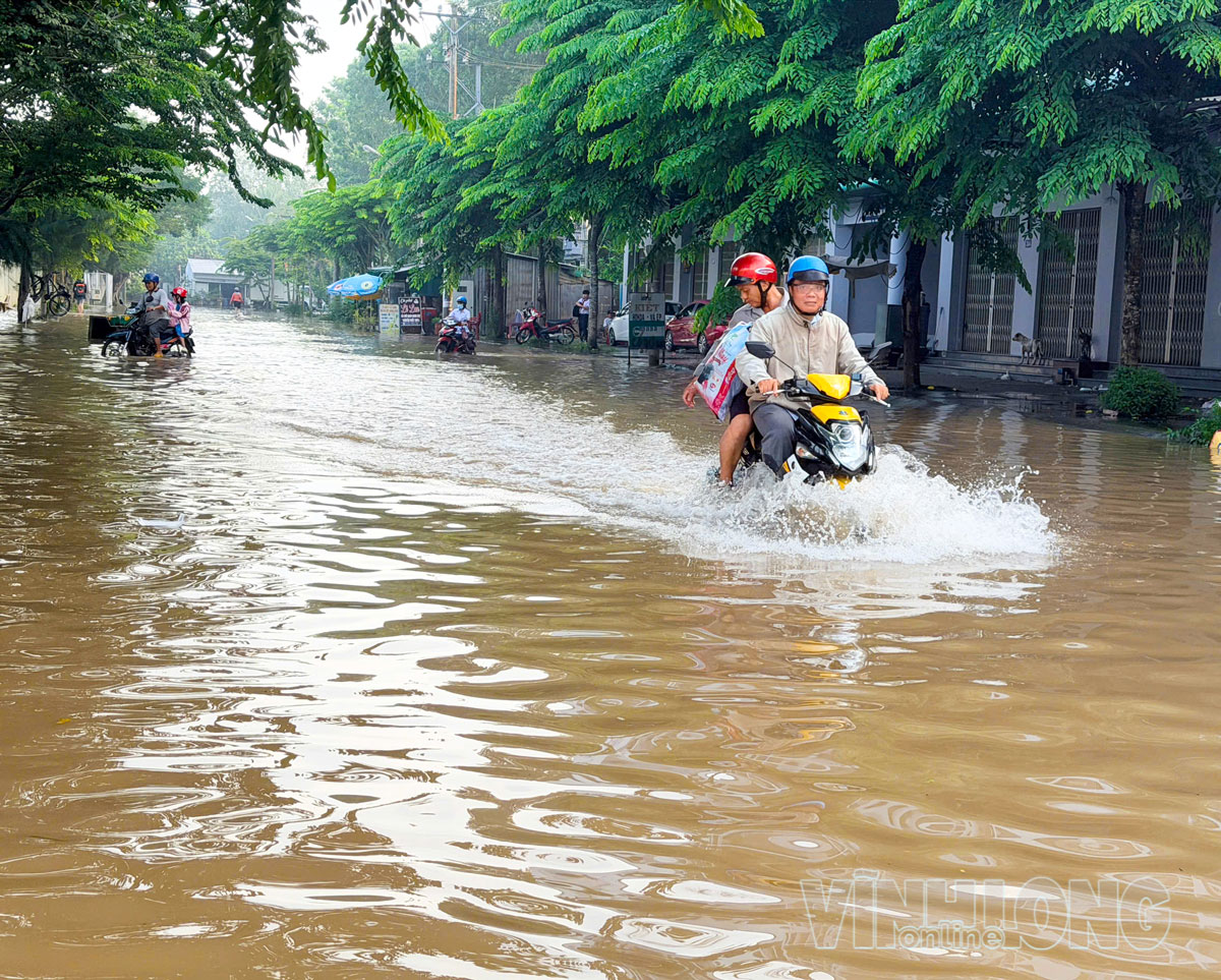 Triều cường dâng cao, người dân chật vật di chuyển qua khu vực ngập.