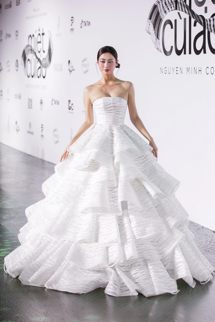 Hoa hậu Lương Thùy Linh với thiết kế bánh tráng rế”, tone màu chủ đạo là trắng, được thiết kế từng tầng cùng độ cong mềm đặc trưng tạo nên vẻ ngoài bồng bềnh, thướt tha - Ảnh: KIẾNG CẬN TEAM

