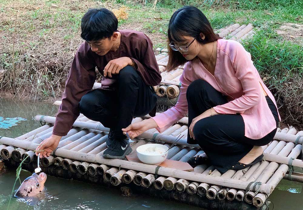 Từ những hiệu lệnh, thói quen mà vật nuôi trong các gia đình ở cồn Sơn có những đặc tính thú vị, như đàn cá ăn cơm bằng muỗng của anh Nguyễn Ngọc Chiến, nhà vườn Song Khánh. Ảnh: Kiều Mai