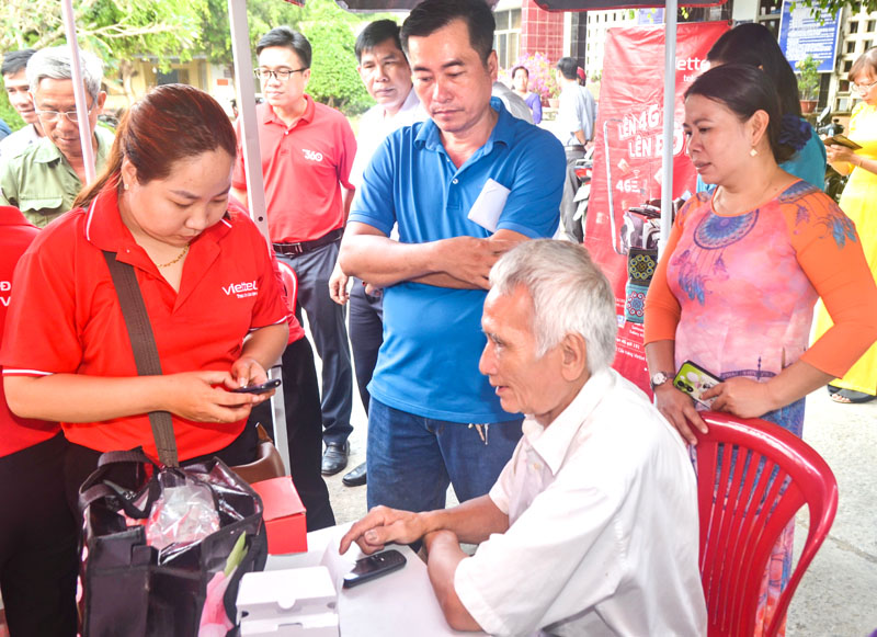 Nhân viên Viettel hỗ trợ người dân cài đặt các phần mềm vào điện thoại thông minh để tham gia chuyển đổi số.