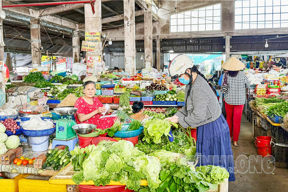 Mưa kéo dài khiến giá rau tại chợ có xu hướng tăng. Trong ảnh: Tiểu thương mua bán rau tại chợ Vũng Liêm (xã Trung Thành).