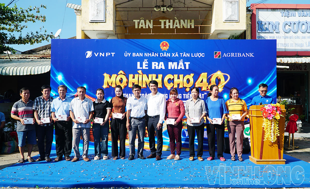 Đại biểu trao loa thông báo thanh toán của VNPT cho các tiểu thương tại chợ.
