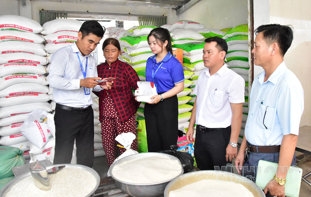Lãnh đạo UBND xã Đôn Châu và đơn vị VNPT hướng dẫn tiểu thương Ngô Thị Kim Oanh cài đặt mã QR kết nối loa thông báo thanh toán.