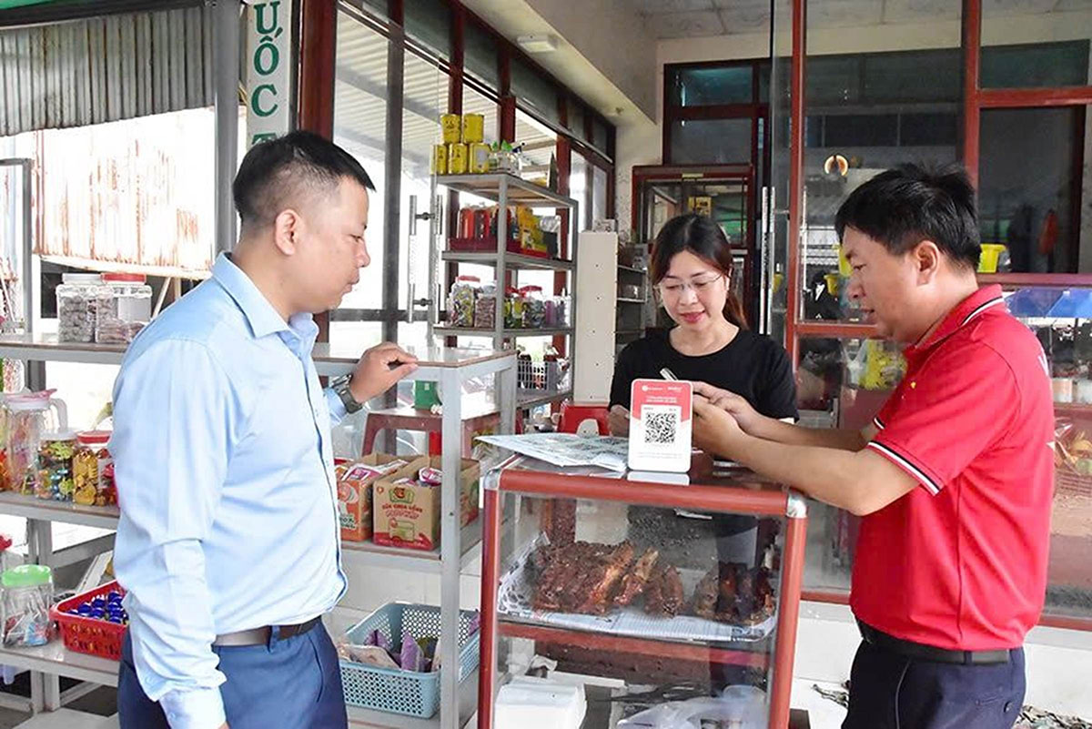 Nhân viên Viettel hỗ trợ tiểu thương chợ Nhị Long dùng phương thức thanh toán không dùng tiền mặt.