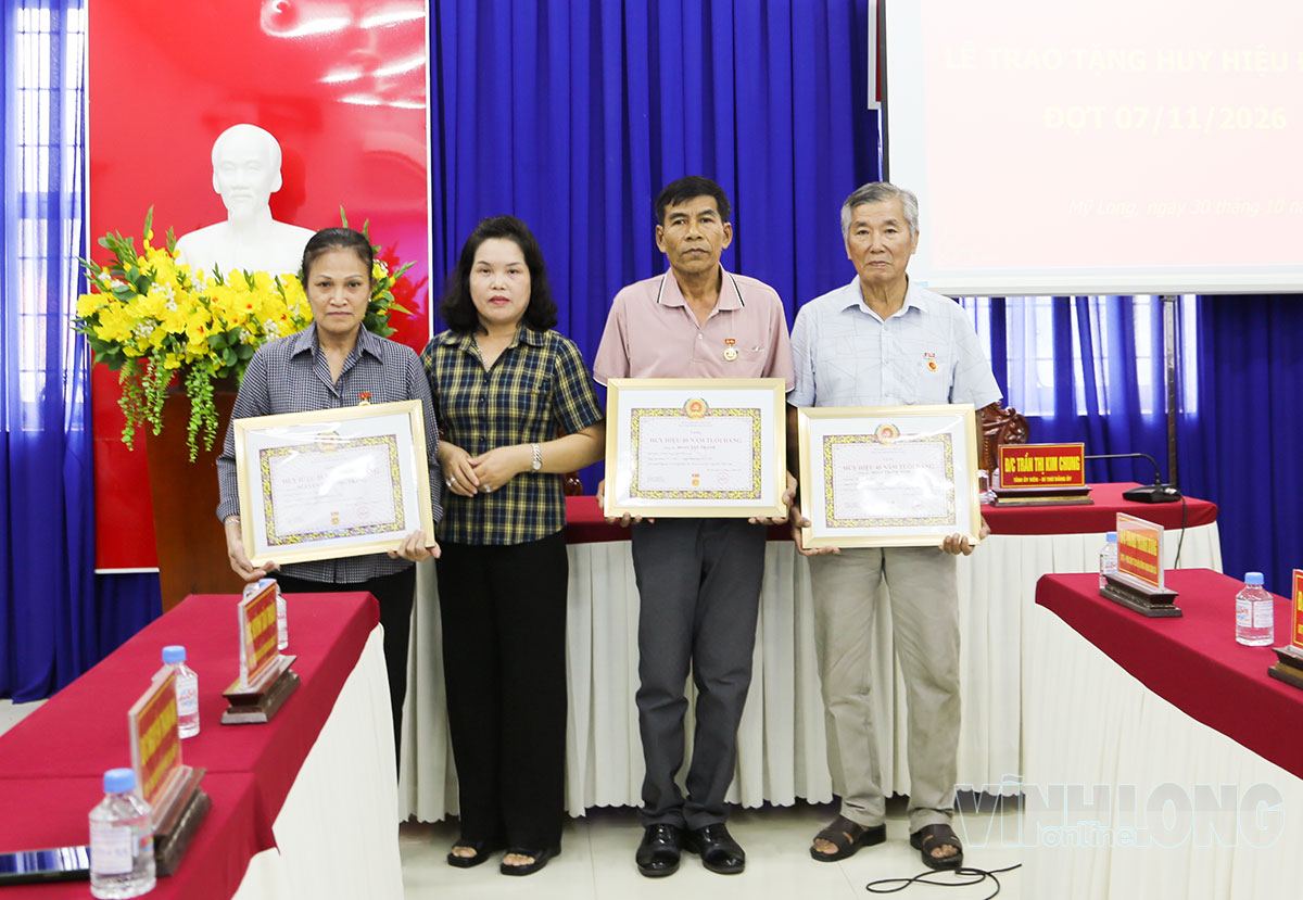 Đồng chí Trần Thị Kim Chung- Tỉnh ủy viên, Bí thư Đảng ủy xã Mỹ Long trao Huy hiệu Đảng cho đảng viên 40 năm tuổi Đảng.