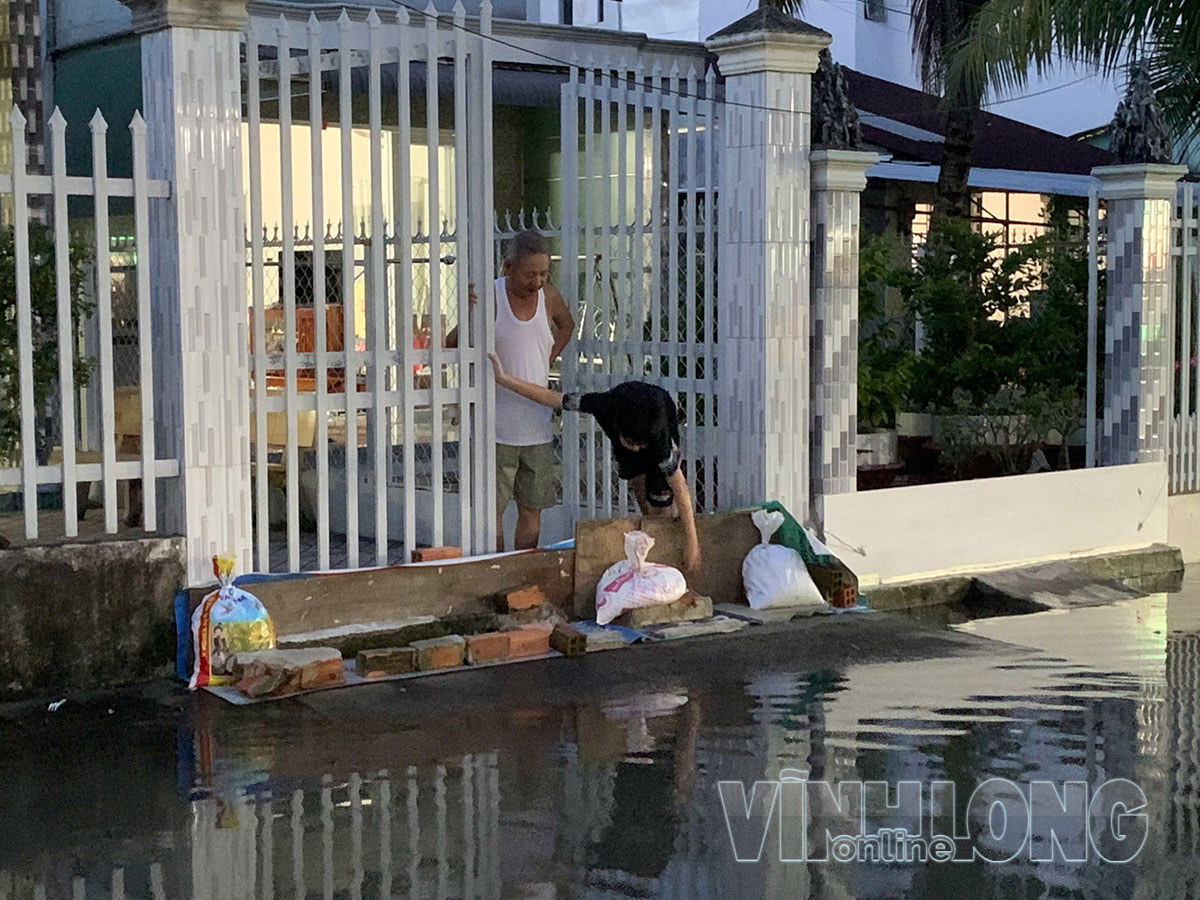 Người dân dùng bao cát, ván gỗ đắp “đê” chắn nước tràn vào nhà.