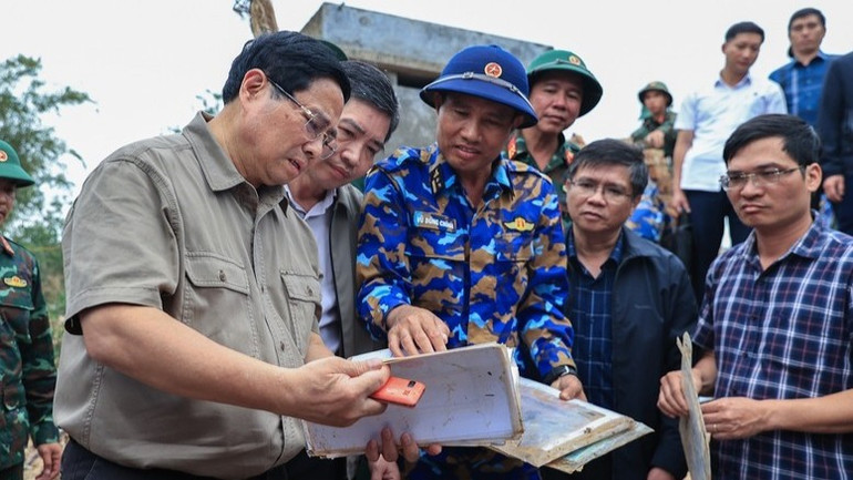 Thủ tướng Phạm Minh Chính xúc động xem những vật dụng của người dân còn sót lại sau lũ lụt. (Ảnh: VGP/Nhật Bắc)