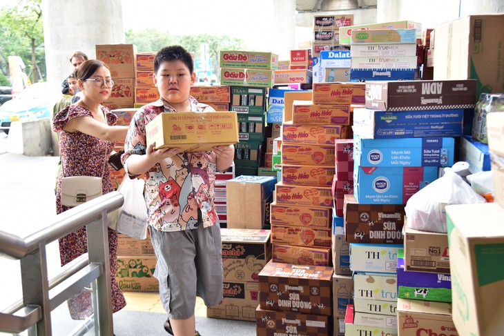 Minh Kiệt (10 tuổi) bưng trên tay một thùng bánh nhỏ quyên góp cho cô chú ở vùng lũ lụt miền Trung

