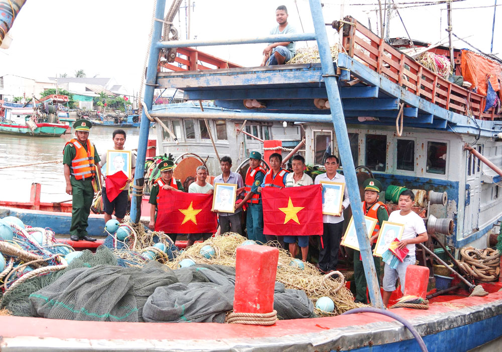 Cán bộ, chiến sĩ Bộ đội Biên phòng tỉnh Vĩnh Long phối hợp Ban Quản lý Cảng cá Định An tuyên truyền IUU, tặng cờ, ảnh Bác đồng hành ngư dân vươn khơi bám biển tại Cảng cá Định An (xã Đại An).