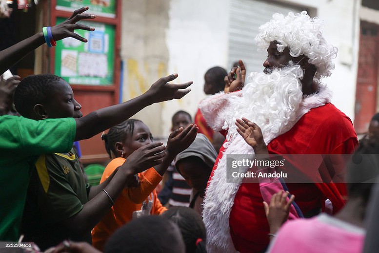 Nghệ sĩ Thierno Gueye trong trang phục ông già Noel phát kẹo cho trẻ em trong một khu dân cư thu nhập thấp tại quận Yoff, Dakar, Senegal trước thềm Giáng sinh.