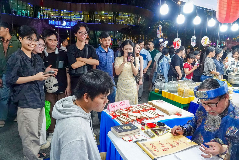 Nghệ nhân viết chữ thư pháp tặng du khách. Ảnh: DUY KHÔI