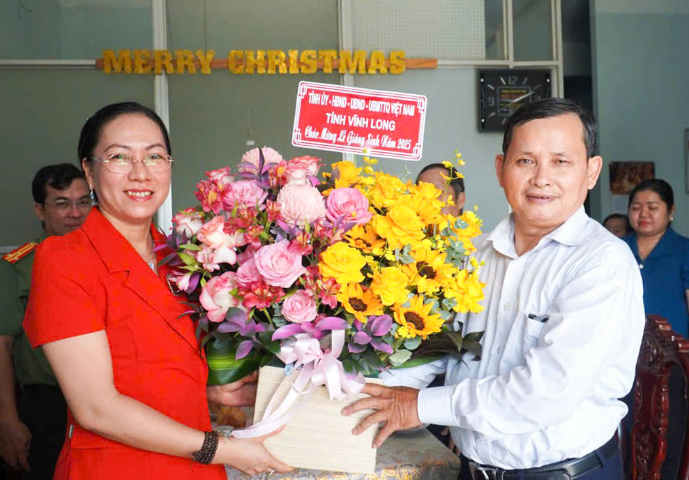 Phó Trưởng đoàn phụ trách Đoàn đại biểu Quốc hội tỉnh Nguyễn Thị Yến Nhi tặng hoa chúc mừng Giáng sinh Chi Hội Tin lành xã Hưng Nhượng. Ảnh: PHAN HÂN.