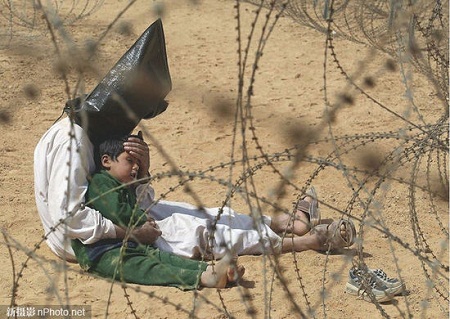 2003: Một người đàn ông Iraq vỗ về đứa con trai trong một trại giam tù nhân chiến tranh ở An Najaf.