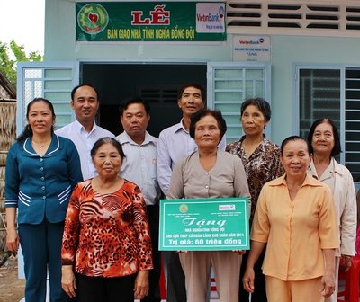 Bà Thanh (cầm bảng) vui mừng trong căn nhà “Nghĩa tình đồng đội”.