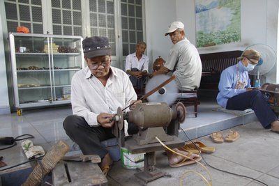 Ông Sáu Đình đang làm cưa mới. Phía sau là khách hàng đang chờ lấy lưỡi cưa.