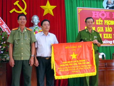 Ông Nguyễn Văn Vịnh- Chủ tịch UBND kiêm Trưởng Ban chỉ đạo phòng chống tội phạm Phường 1 (áo trắng) nhận cờ thi đua Bộ Công an tặng.     