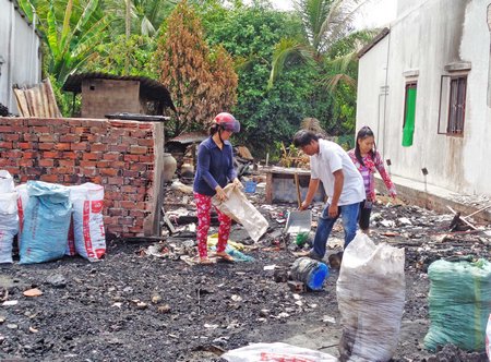 Gia đình anh Sâm dọn dẹp đống tro tàn sau vụ hỏa hoạn.