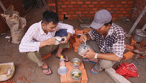 Anh Tú (trái) thường theo cha làm phụ hồ. Đây là bữa cơm trưa của hai cha con