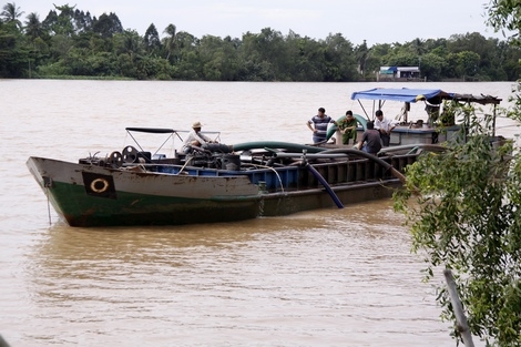 Lực lượng chức năng đang kiểm tra xà lan không số bơm cát trái phép tại Mang Thít.