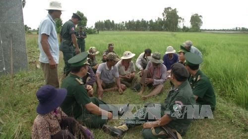 Lực lượng vũ trang và bà con hai bên biên giới gặp gỡ, thăm hỏi nhau dưới chân cột mốc 303 huyện Giang Thành và tỉnh Kam Pốt. Ảnh: Lê Sen/TTXVN