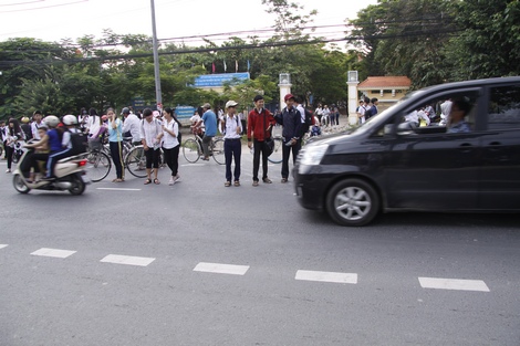 Từng tốp học sinh dựa nhau sang đường. Các phương tiện cơ giới đường bộ thì vừa chạy vừa bấm kèn inh ỏi, không nhường đường cho học sinh.