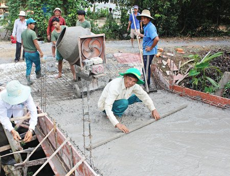 Ông Sáu Dũng (ngồi cào hồ) cùng nhân dân xây cầu nối từ Ấp 6B qua ấp Cái Sơn.