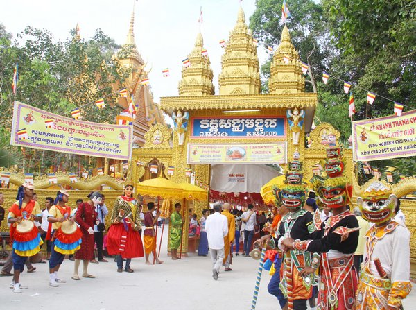 Các thanh niên Khmer đeo mặt chằn và mặt hề đón khách từ ngoài cổng chùa. Bên trong, các thiếu nữ mặc đồ truyền thống dân tộc chắp tay chào đón khách.