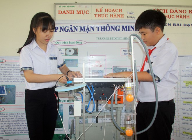 Khánh và Dung lắp đặt thử nghiệm hệ thống đập ngăn mặn thông minh sử dụng năng lượng mặt trời.