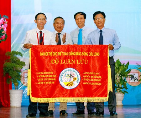Đơn vị Bến Tre (trái) trao cờ luân lưu tổ chức Đại hội TDTT ĐBSCL lần thứ 8 do tỉnh Vĩnh Long đăng cai tổ chức, trước sự chứng kiến của ông Phạm Văn Tuấn- Phó Tổng cục trưởng Tổng Cục TDTT (thứ hai bên trái) và ông Nguyễn Kiều Linh- Cục trưởng Cục Công tác phía Nam.