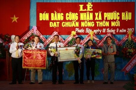 Đồng chí Nguyễn Bách Khoa- Ủy viên Thường vụ Tỉnh ủy, Trưởng Ban Tuyên giáo Tỉnh ủy (bìa trái) và ông Trần Hoàng Tựu- Tỉnh ủy viên, Phó Chủ tịch UBND tỉnh (bìa phải) trao quyết định công nhận đạt chuẩn NTM và khen thưởng công trình phúc lợi trị giá 1 tỷ đồng cho xã Phước Hậu.