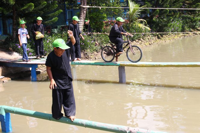 Các em thiếu nhi thích thú với trò chơi đi cầu khỉ, đạp xe đạp vượt sông.