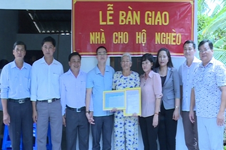 Chính quyền địa phương và Mạnh thường quân chụp ảnh lưu niệm với bà Lê Thị Ba trong lễ bàn giao nhà.