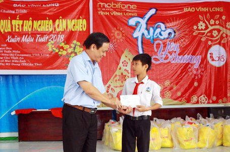 Dịp này, Báo Vĩnh Long còn trao tặng 1 suất học bổng cho học sinh có hoàn cảnh đặc biệt khó khăn. Trong ảnh: ông Phạm Hoàng Khải -Tổng biên tập Báo Vĩnh Long trao học bổng cho em Lê Quốc Thịnh.