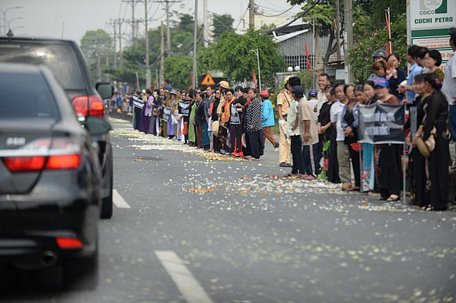 Người dân rải hoa hai bên đường khi đoàn xe chở linh cữu đi qua - Ảnh: THUẬN THẮNG