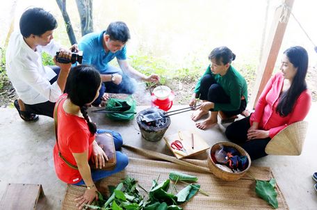 Chị Bảy Muôn (thứ hai, từ phải qua) hướng dẫn du khách làm bánh. Ảnh: DUY KHÔI