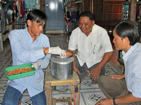 Anh Lê Minh Sang (trái) bên chiếc máy xay tôm khô tự chế.