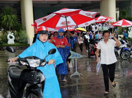 Chiều 26/6, mưa không ngớt hạt, thí sinh tại điểm thi Trường ĐH Xây dựng Miền Tây được tình nguyện viên che mưa.