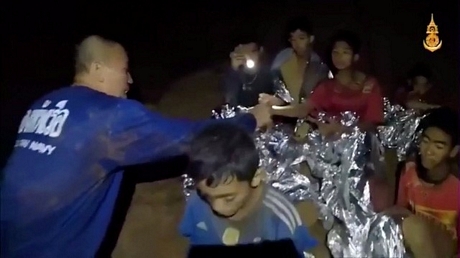 Hai thành viên của đội cứu hộ soi đèn để chăm sóc cho các cậu bé (Ảnh: Reuters)