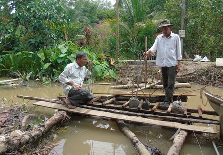  Không chỉ vận động nguồn kinh phí hỗ trợ xây dựng, ông Lợi (đeo kính) còn trực tiếp cùng người dân xây dựng cầu Rạch Ngãi giữa.