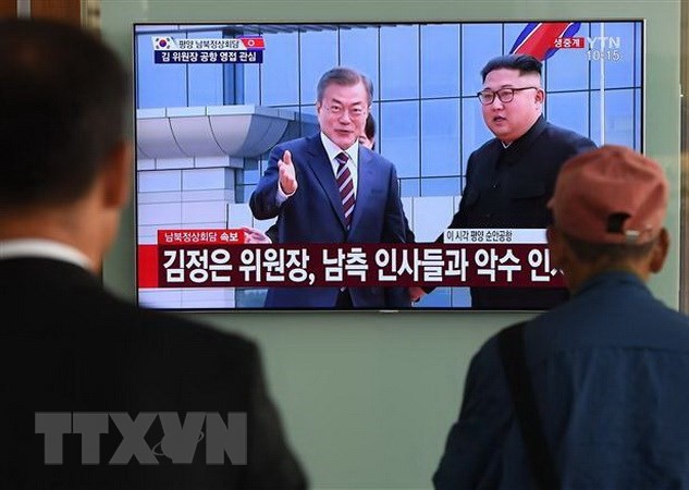 Người dân Hàn Quốc theo dõi hình ảnh truyền hình trực tiếp Nhà lãnh đạo Triều Tiên Kim Jong-un (phải, phía xa) đón Tổng thống Hàn Quốc Moon Jae-in (trái, phía xa) tại sân bay quốc tế Bình Nhưỡng ngày 18/9/2018. (Ảnh: AFP/ TTXVN)