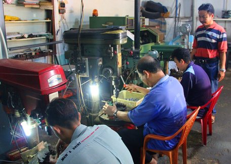 Ông Đặng Hoàng Sơn (bìa phải) quan sát quy trình sản xuất thiết bị tiết kiệm nhiên liệu.