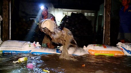 Nhà dân bị ngập, phải dùng bao cát chắn nước và nước rỉ vào phải thức đêm tát nước.